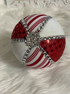 a red and white christmas ornament sitting on top of a fur covered floor