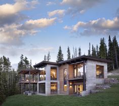 a modern house on top of a hill with trees in the background