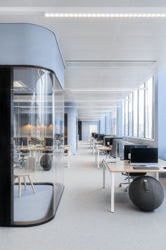 an empty office with desks, chairs and computers on the tables in front of glass walls