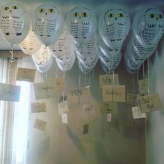 a bunch of balloons with writing on them hanging from the ceiling in front of a window