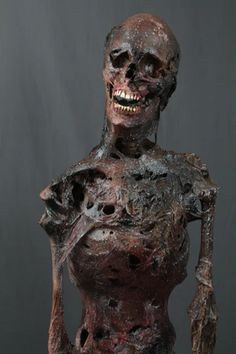 a sculpture of a human being covered in mud and dirt, with one hand on his hip