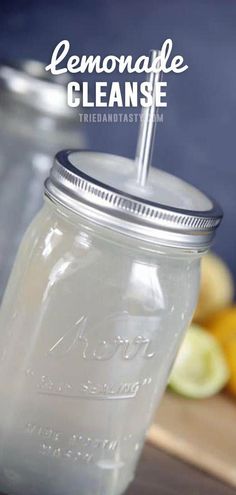 a mason jar with a straw in it sitting on a cutting board next to lemons