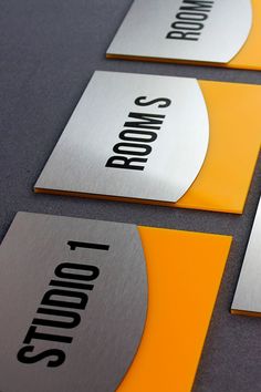 three metal business cards sitting on top of a gray table next to an orange and white sign