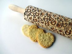 two heart shaped cookies next to a rolling pin