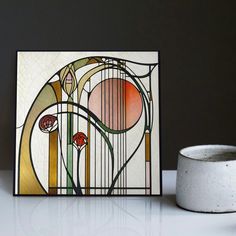 a white vase sitting on top of a table next to a stained glass window panel