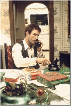 a man sitting at a table talking on a cell phone while holding a black teapot