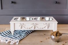 two metal bowls with food in them on a wooden floor next to a blue and white towel