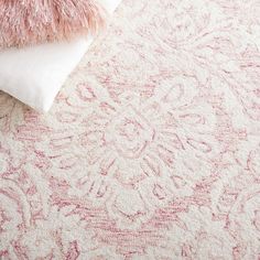 a pink and white rug with pillows on it