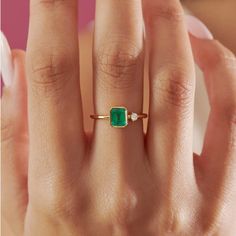 a woman's hand with a ring on it and a green stone in the middle