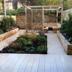 a wooden bench sitting next to a garden filled with lots of plants and flowers on top of a hard wood floor