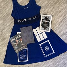 a blue dress with various items on it sitting on a bed next to a book