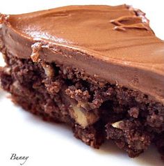 a close up of a piece of cake on a white plate with chocolate frosting