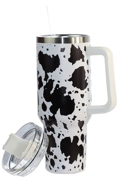 a black and white cow print travel mug with lid next to a glass cup holder