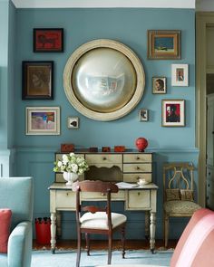 a living room with blue walls and pictures on the wall, including an antique desk