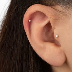 a woman's ear with three small white stones on it