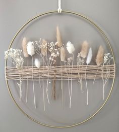 a circular display with dried flowers and plants on it's side, hanging from the wall