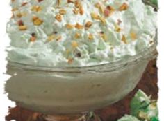 a bowl filled with whipped cream sitting on top of a table next to green leaves