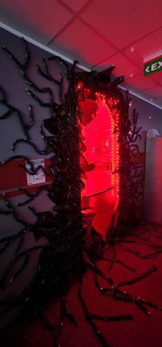 a red light is shining in the corner of a room with black branches on the floor