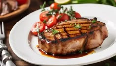 a white plate topped with meat covered in marinara sauce next to tomatoes and cherry tomatoes