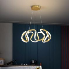 a modern chandelier hanging from the ceiling in a kitchen with dark blue walls