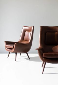 two brown leather chairs sitting next to each other