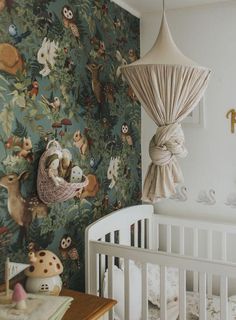 a baby's room with a crib and wallpaper that has animals on it