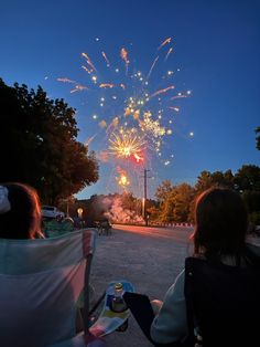 two people sitting on chairs watching fireworks in the sky