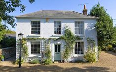 a white house with ivy growing on it's walls and windows in the front