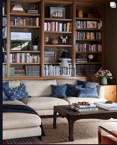 a living room filled with lots of furniture and bookshelves covered in shelves full of books