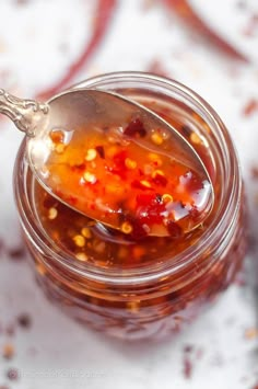 a spoon with some food in it on top of a glass jar filled with liquid