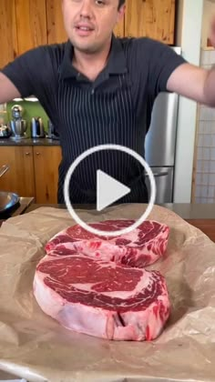 a man standing in front of a table with raw meat on it and pointing to the camera