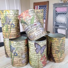 several tin cans are stacked on top of each other with butterflies painted on the lids