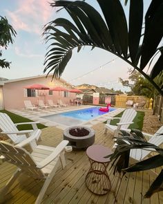 a deck with chairs and a fire pit next to a swimming pool in the backyard