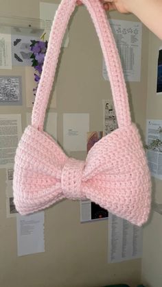 a pink knitted bow tie hanging from a wall