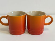 two orange coffee mugs sitting side by side