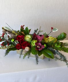 an arrangement of flowers and greenery on a table