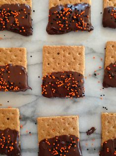 crackers with chocolate and sprinkles are arranged on a white marble surface