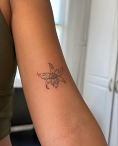 a woman's arm with a small flower tattoo on the left side of her arm