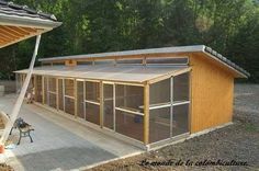 a small wooden building sitting on top of a dirt field next to a lush green forest