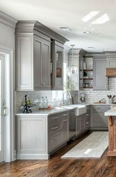 a kitchen filled with lots of gray cabinets and counter top space next to a wooden floor