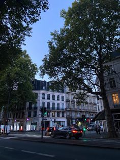 cars are parked on the street in front of tall buildings and trees at night time