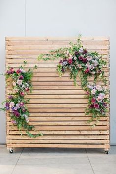 a wooden wall with flowers and greenery on it