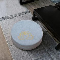 a round ottoman sitting on top of a rug next to a coffee table