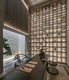 an office with glass blocks on the wall and wooden desks in front of it