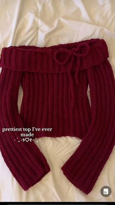 a red knitted sweater with a bow at the waist and bottom, on top of a white sheet