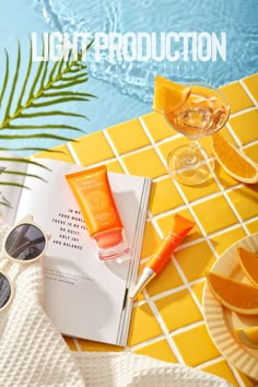 an open book on a table next to some glasses and orange slices with the words light production