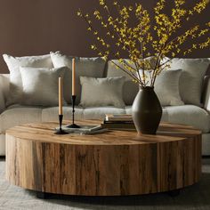 a living room with a couch, coffee table and vase on the floor in front of it