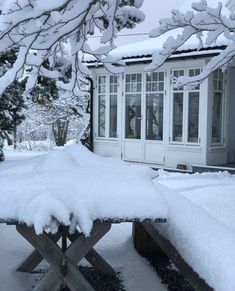 a snow covered bench in front of a house