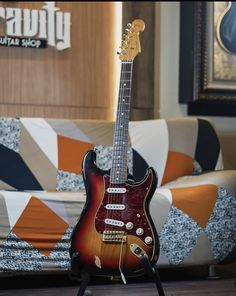 a guitar sitting on top of a stand in front of a couch