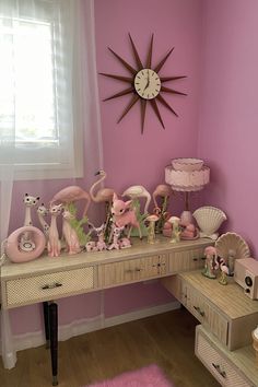 a room with pink walls and toys on the desk